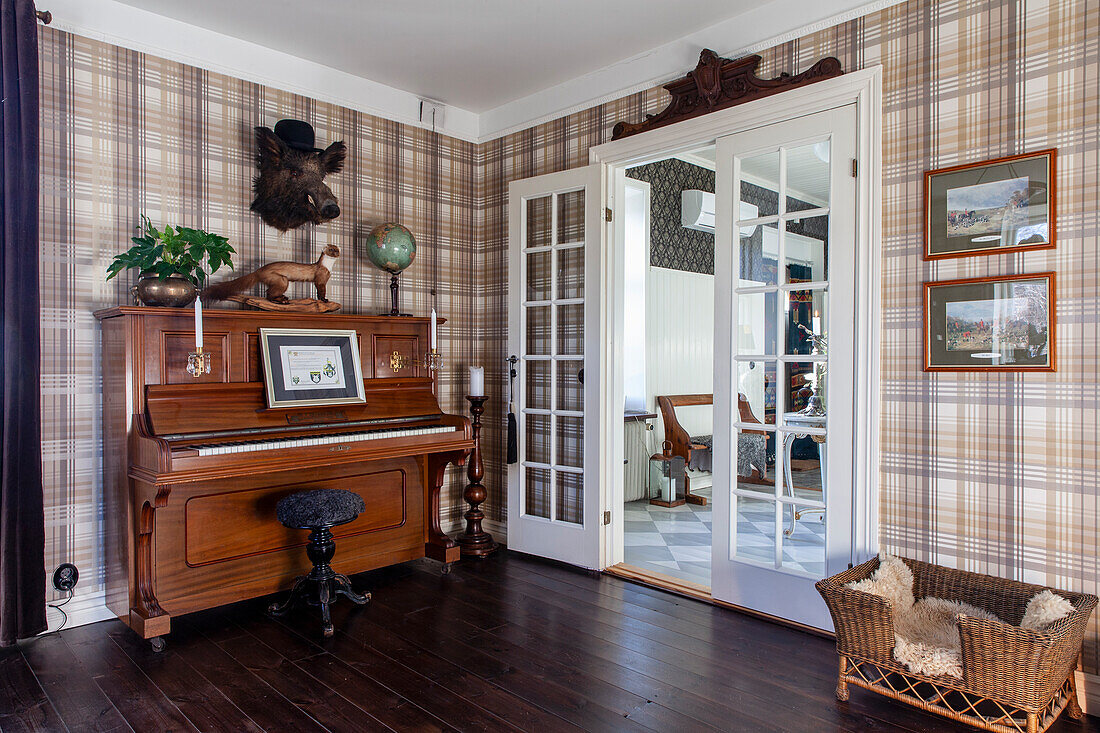 Classic living room with wooden piano, checkered wallpaper and French doors