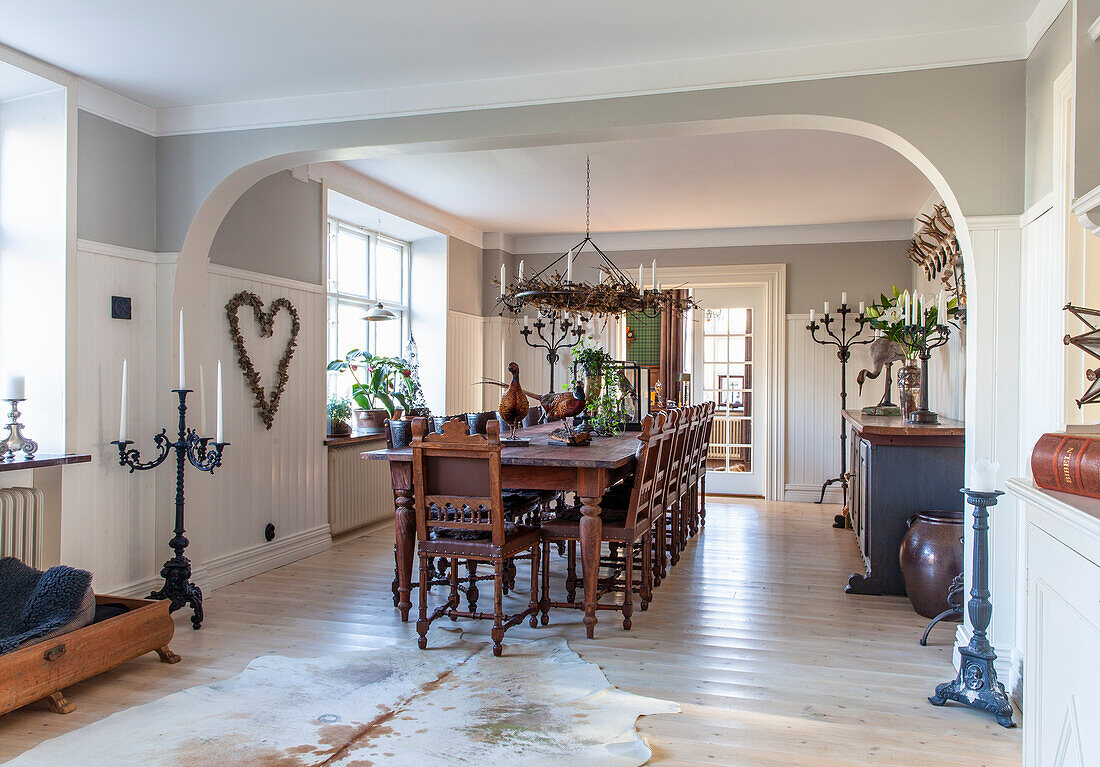 Country-style dining room with rustic wooden table, old wooden chairs and candlesticks