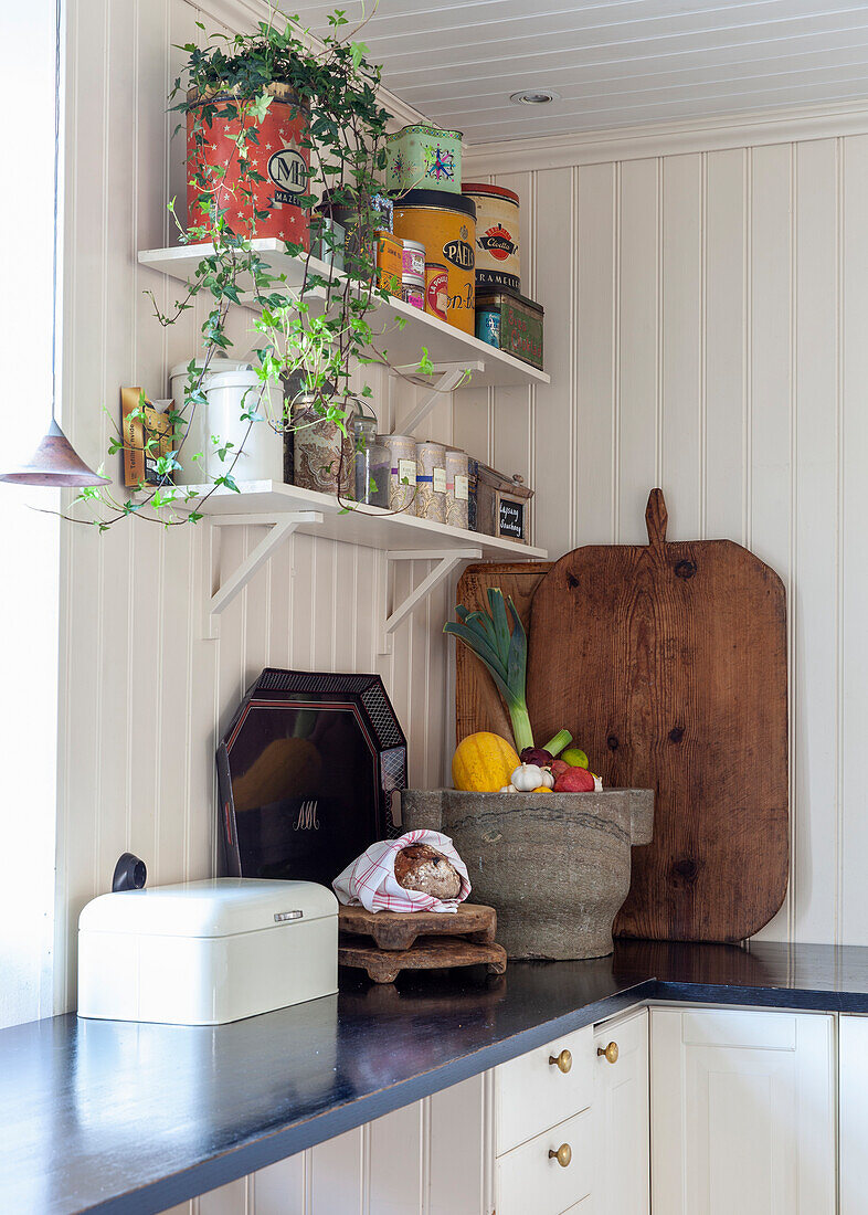 Kitchen with dark countertop, wooden chopping board and shelves with vintage tins