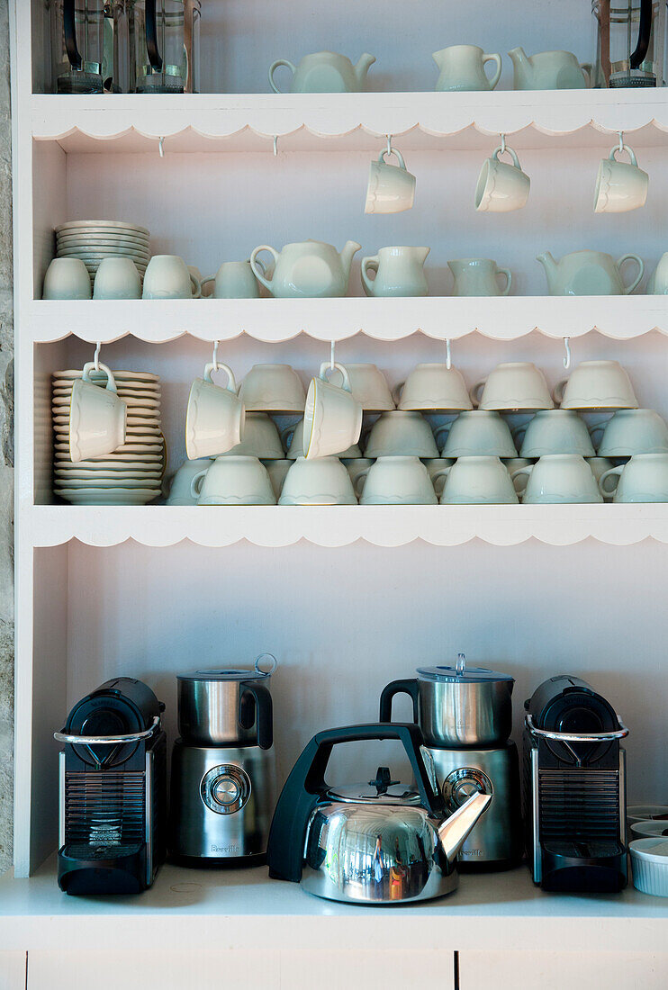 Shelves with white porcelain and coffee machines in the kitchen