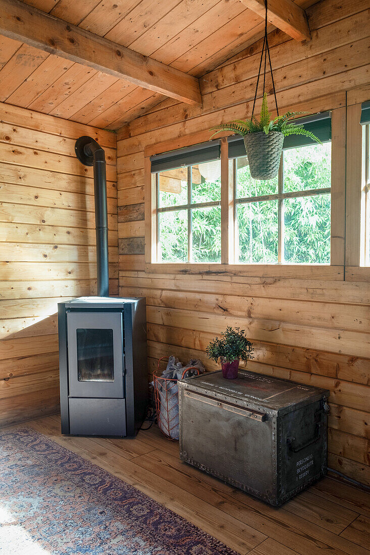 Holzverkleideter Raum mit Kamin, Truhe und Blumenampel