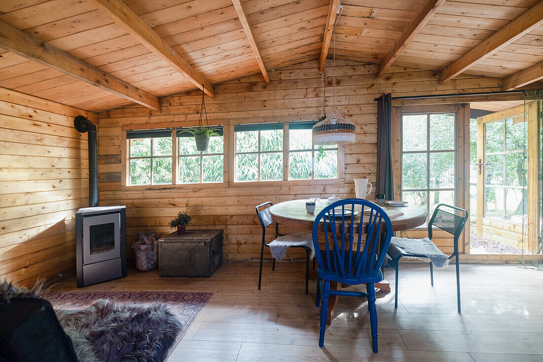 Gemütliches Holzhaus mit rundem Tisch, Stühlen und Ofen