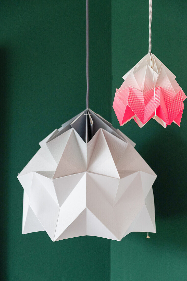 Origami-Deko in Weiß-Grau und Weiß-Pink vor grüner Wand