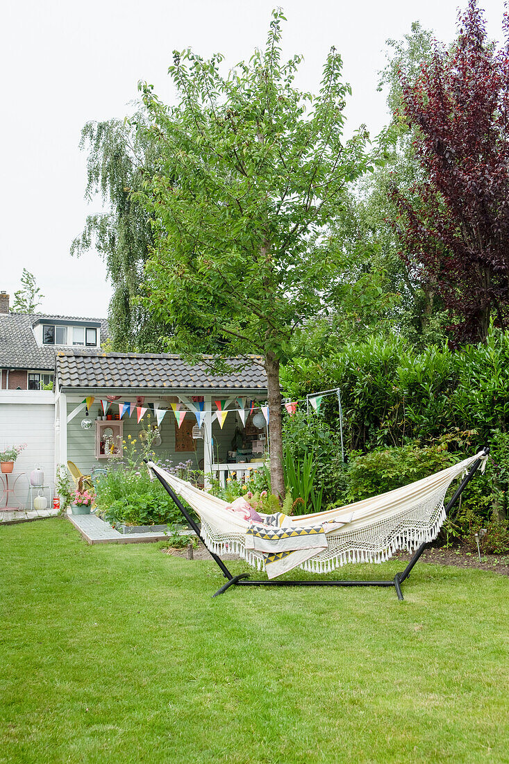 Hängematte im Garten neben einem geschmückten Gartenhaus