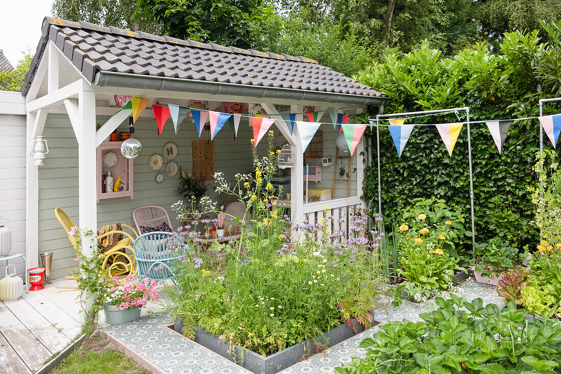 Gazebo with bunting, surrounded by plants and flowerbeds