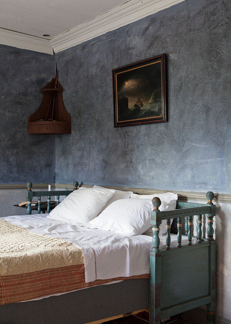 Bed with antique wooden frame in blue-painted bedroom