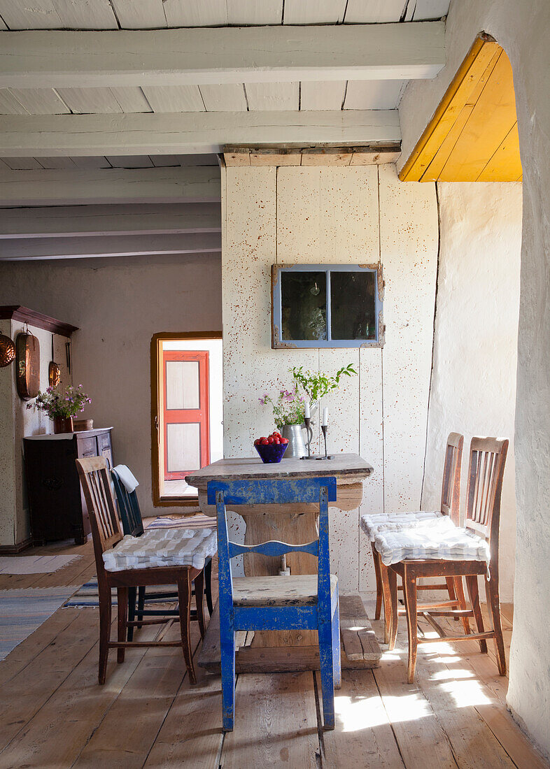 Rustic dining area with different chairs and wooden floorboards