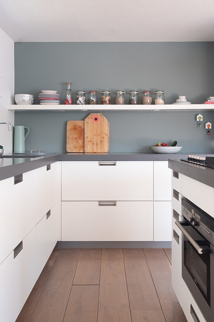 Modern kitchen with white cabinets, grey worktops and wooden floor