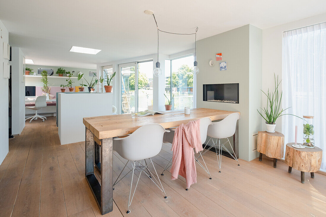 Wooden dining table and white chairs, indoor plants and view of work area