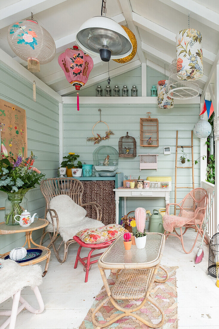 Colourful garden shed with wicker furniture and vintage-style lamps