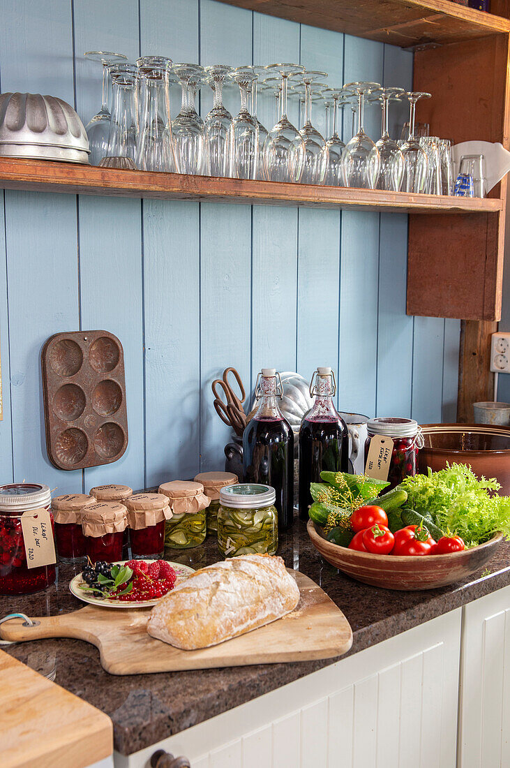 Country kitchen with preserving jars, fresh vegetables and bread on the worktop