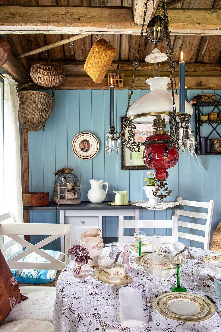 Country-style dining area with antique hanging lamp and blue-painted wood panelling