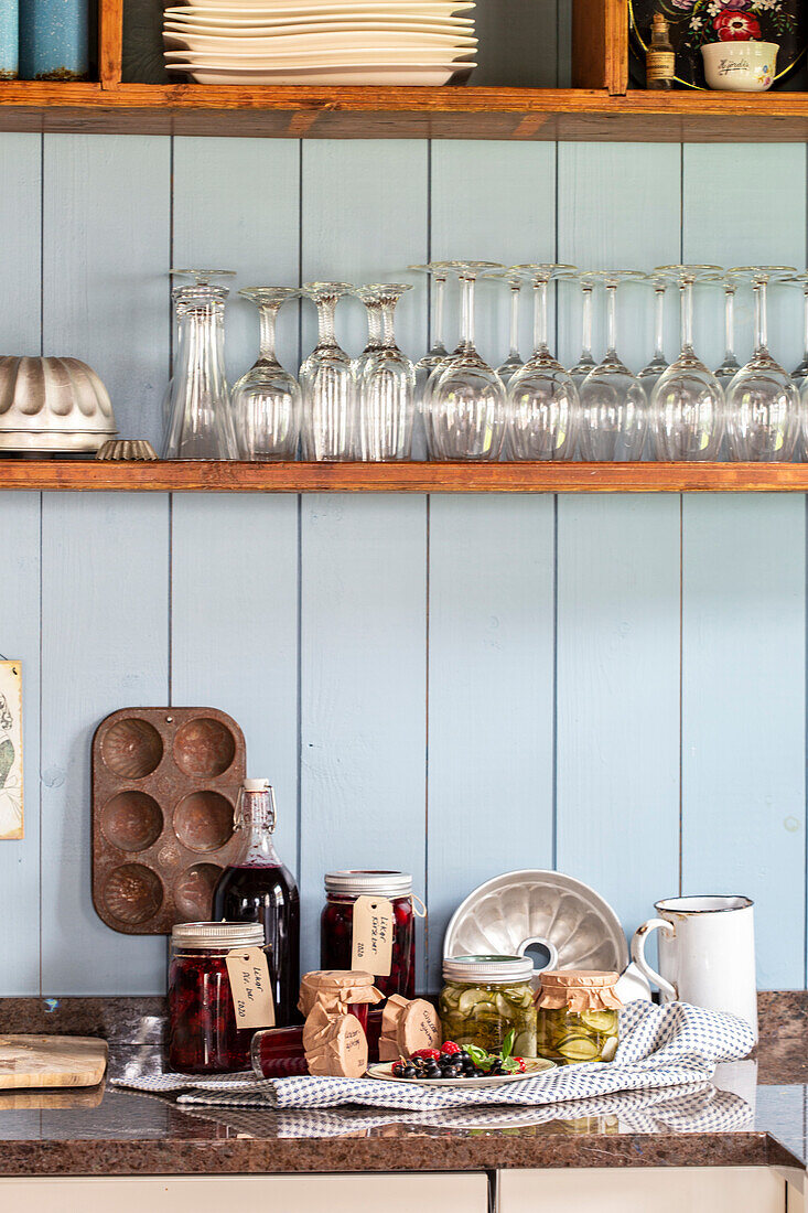 Shelf with jars and homemade preserves on worktop in rustic kitchen