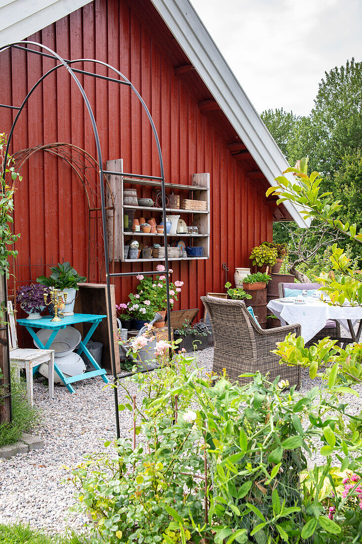 Garden area with red wooden house, shelves and cosy seating area