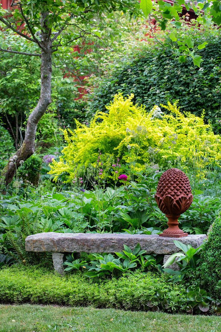 Steinbank mit Terrakotta-Dekoration im grünen Garten