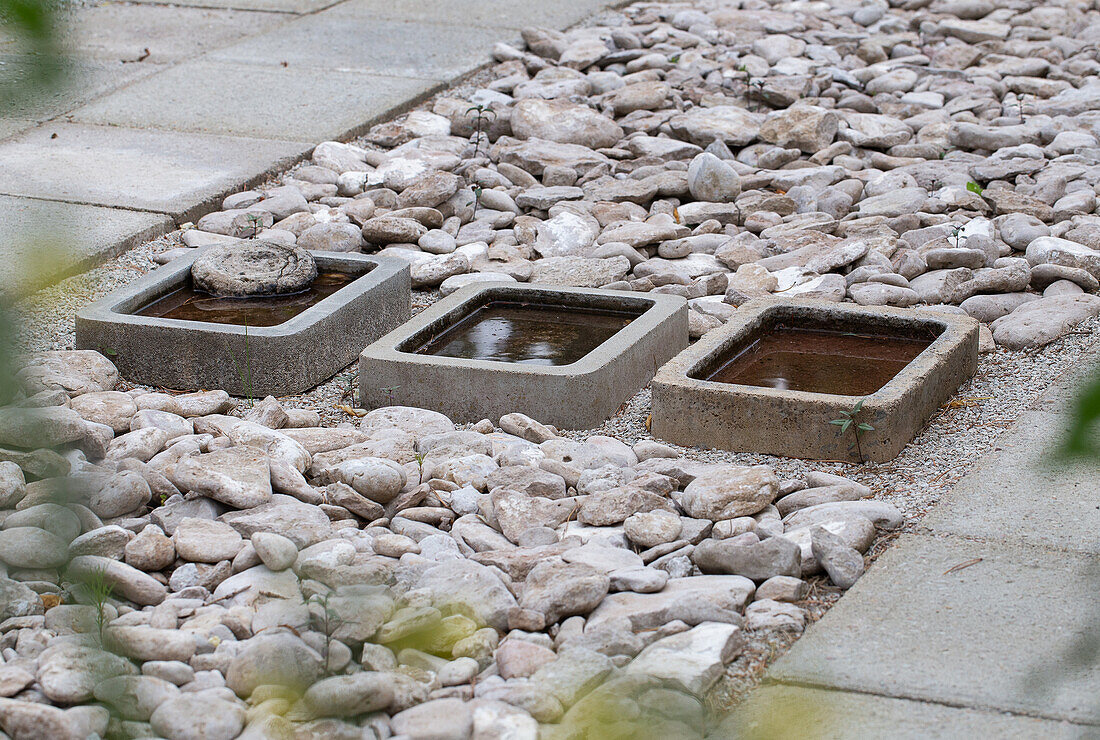 Steinbeet mit drei quadratischen Wasserbecken aus Beton im Garten