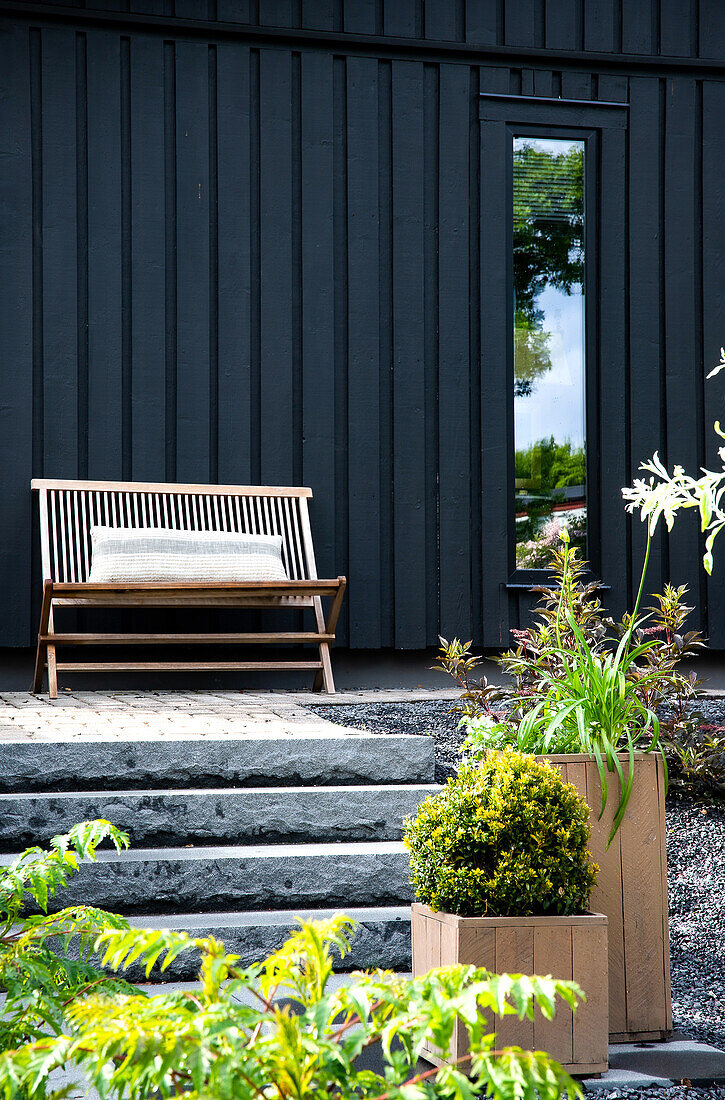 Stone steps, wooden bench on terrace and black façade