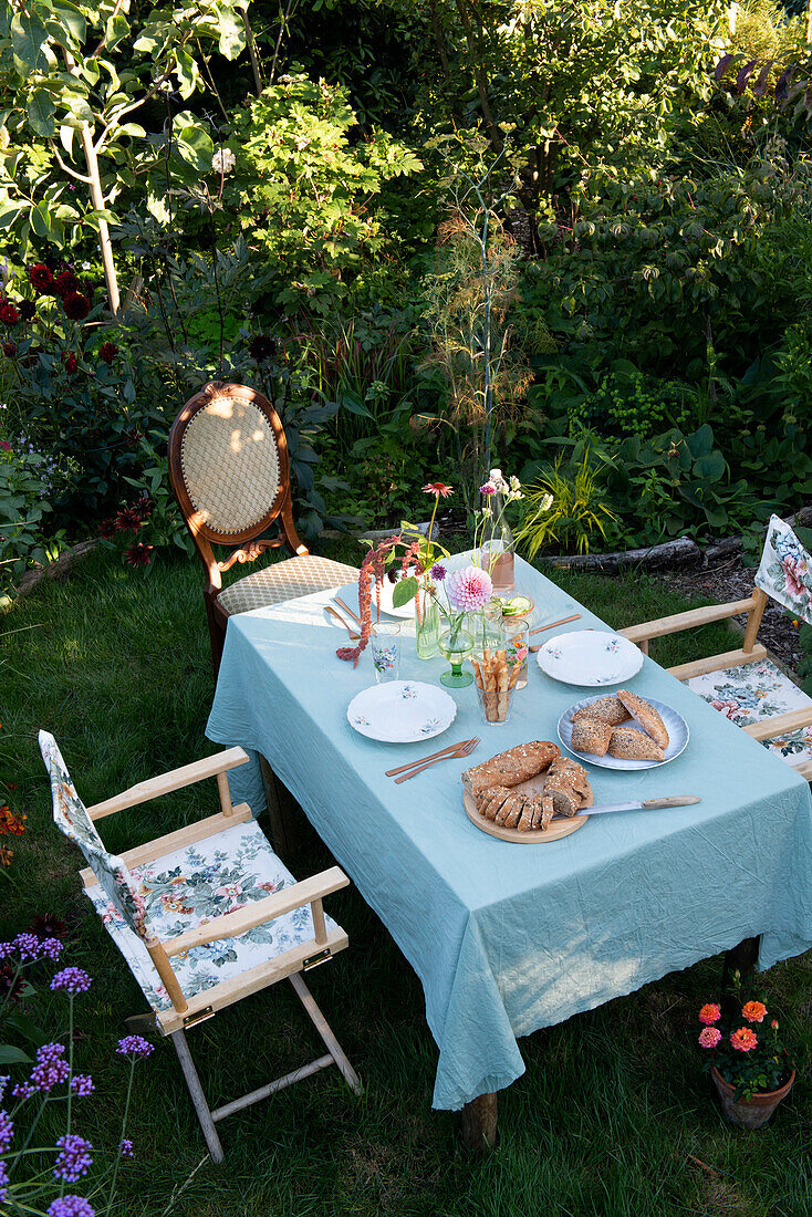 Gedeckter Gartentisch mit Gebäck und frischen Blumen im Sommergarten