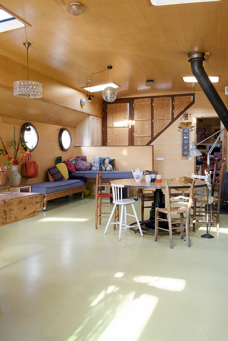 Houseboat living area with wood panelling and round windows