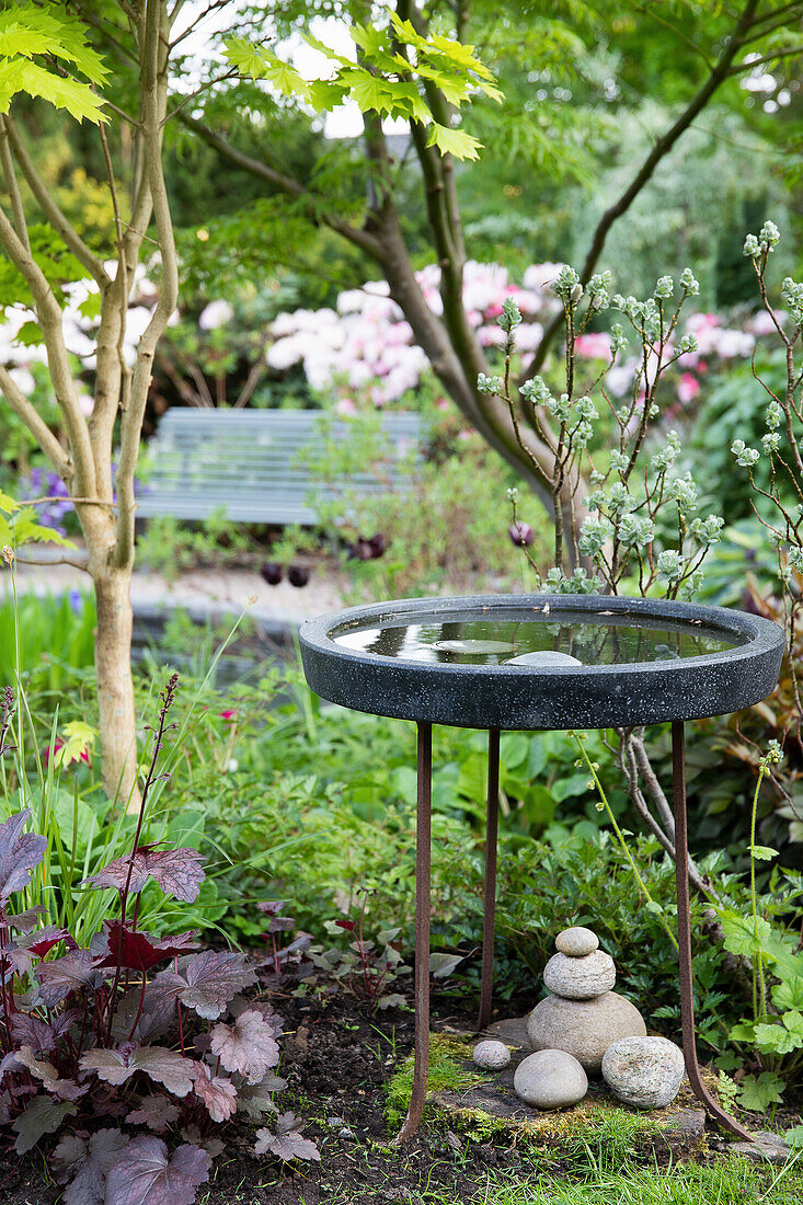 Stone bird bath in a lushly planted garden