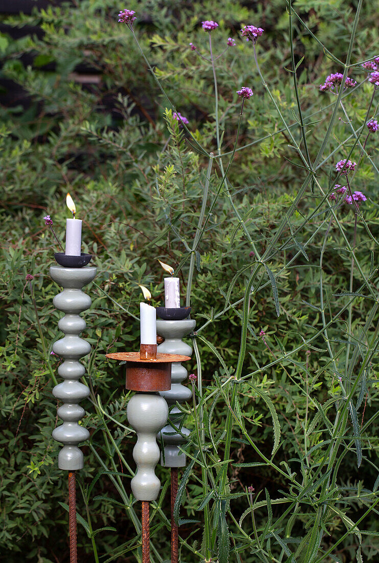 Candlesticks in different heights in the flowering garden bed