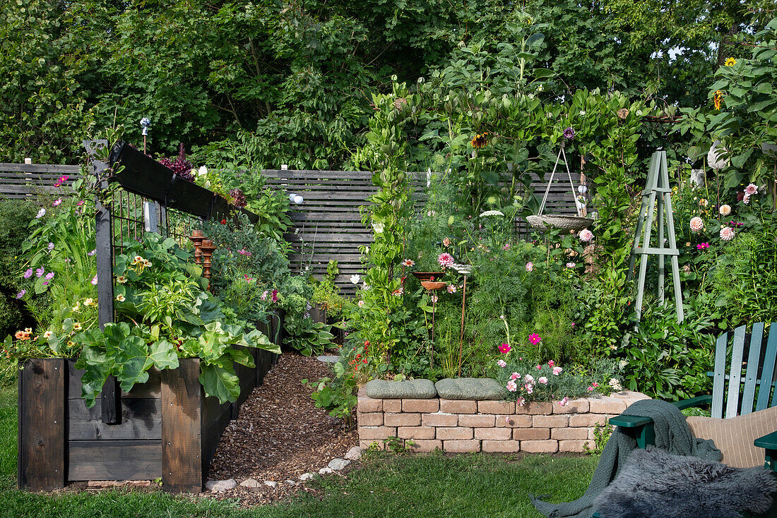 Üppiger Garten mit Blumenbeeten und Hochbeeten im Sommer