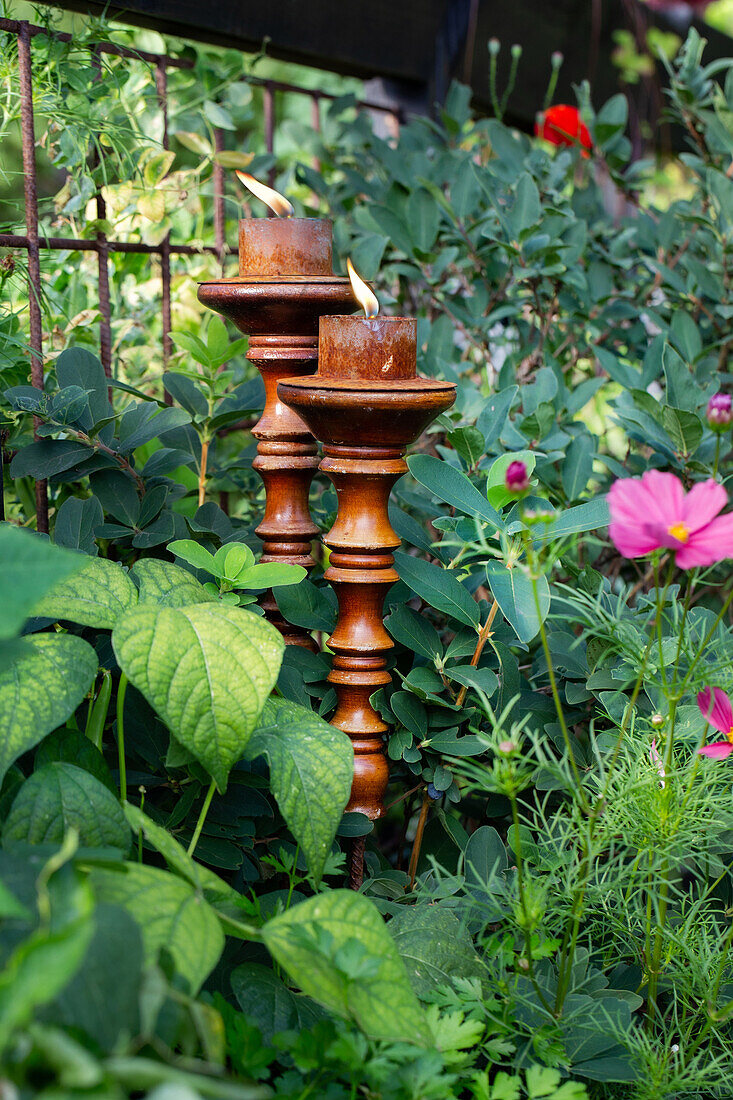 Kerzenhalter aus Holz zwischen Pflanzen im Garten