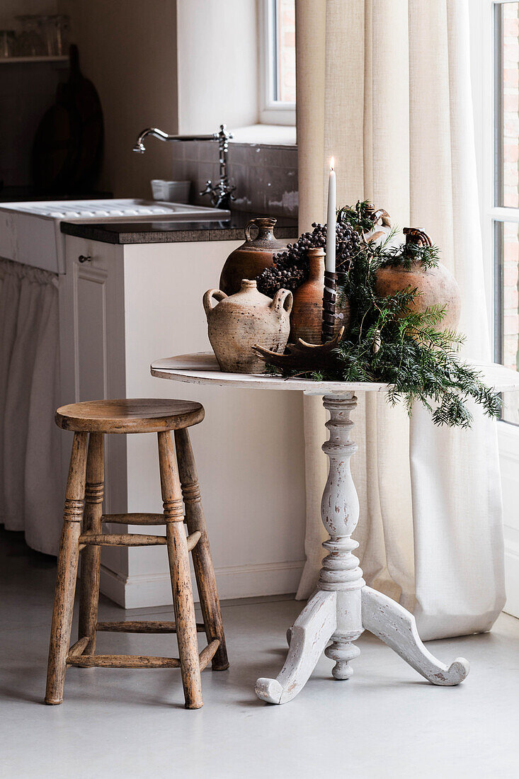 Kitchen corner with rustic table, jugs and fir branches