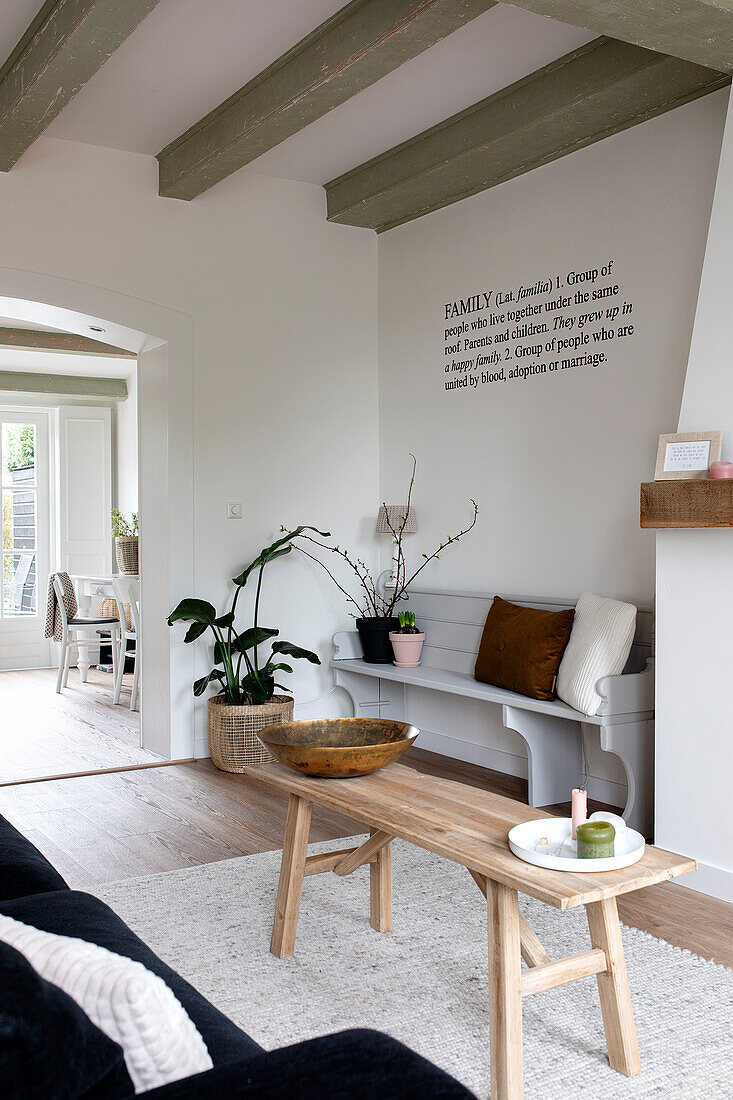 Bright, modern living area with wooden bench, plants and wooden table