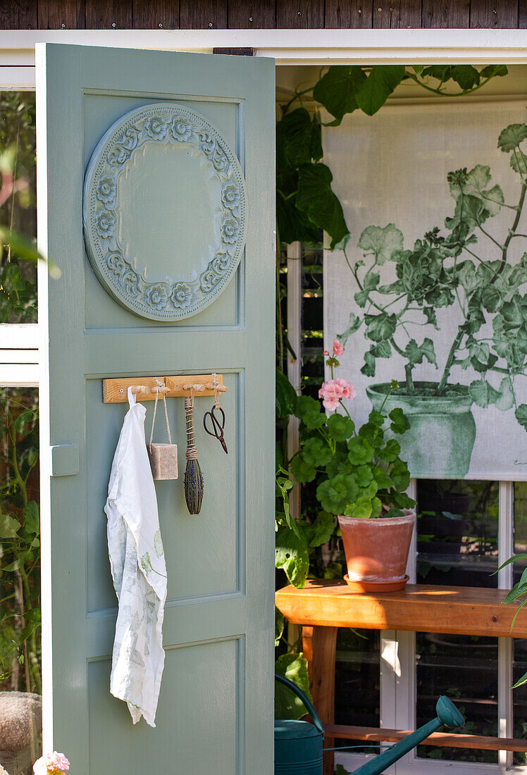 View of garden shed with green-painted door and plant picture