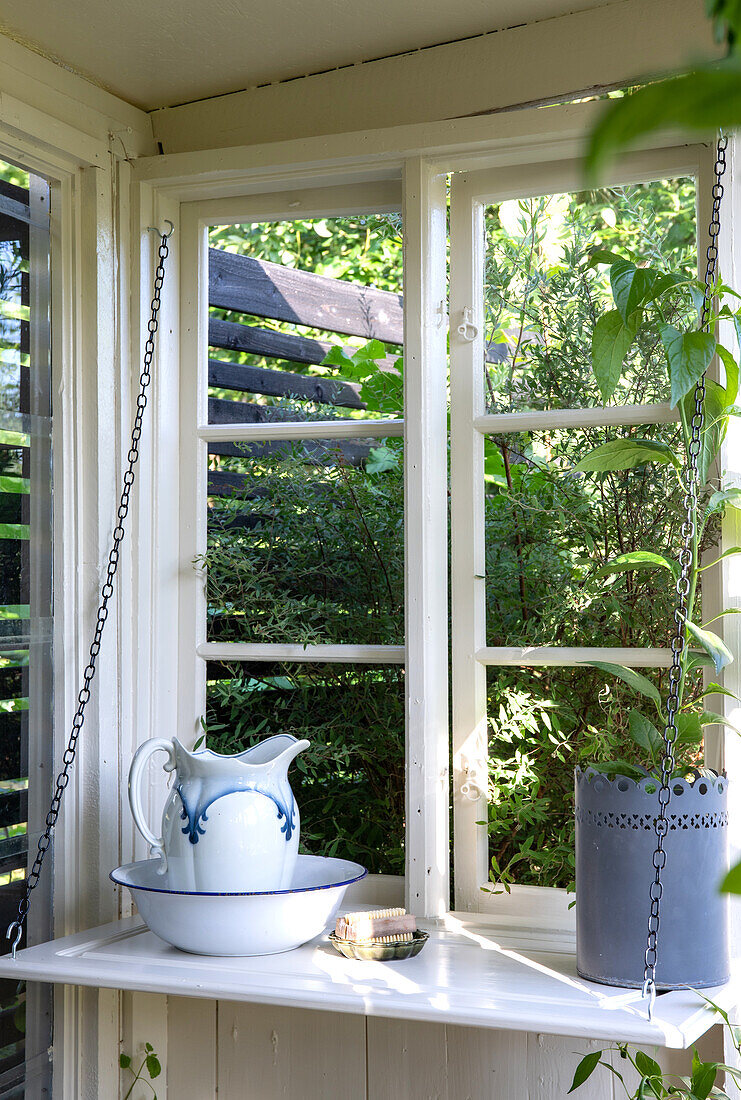 Vintage-Krug und Waschschüssel auf Fensterbrett im Gartenhaus