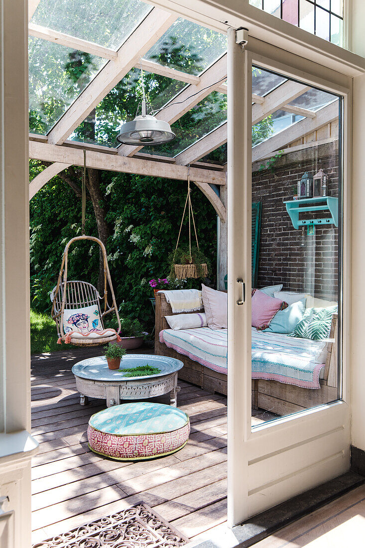 Überdachte Terrasse mit Loungesofa und Hängesessel aus Rattan