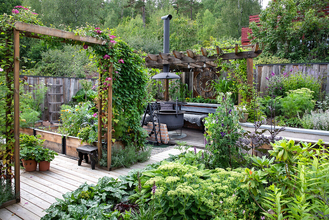 Wooden terrace with lush planting and garden fireplace in the background