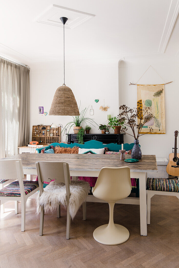 Dining area with large wooden table, various chairs and plants