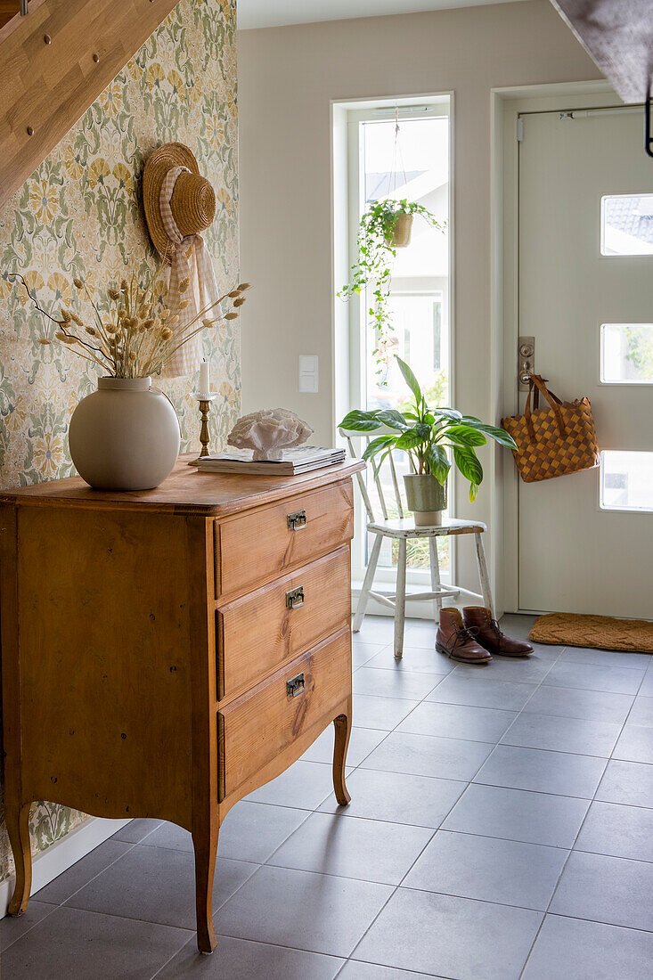 Hallway with vintage chest of drawers and floral wallpaper