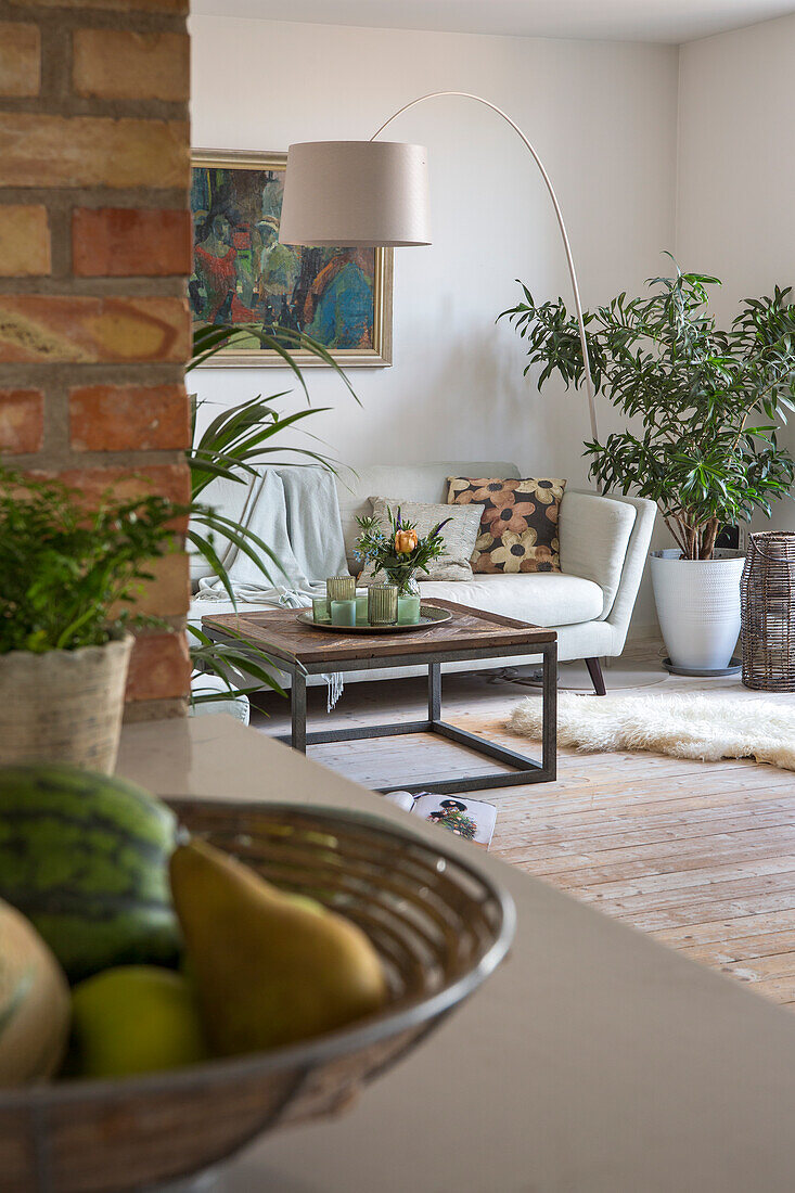 Gemütliches Wohnzimmer mit Ziegelwand, Bogenlampe und Pflanzen