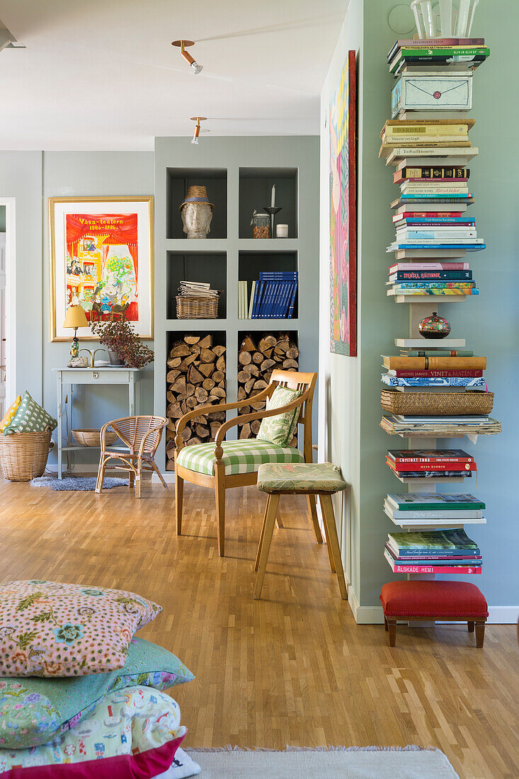 Wohnzimmer mit Wandregal für Bücher, Holzscheite und Stuhl mit Karomuster