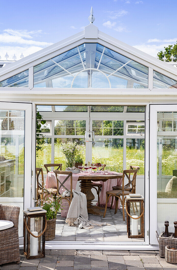 Wintergarten mit Esstisch und Stühlen, Blick in den Garten