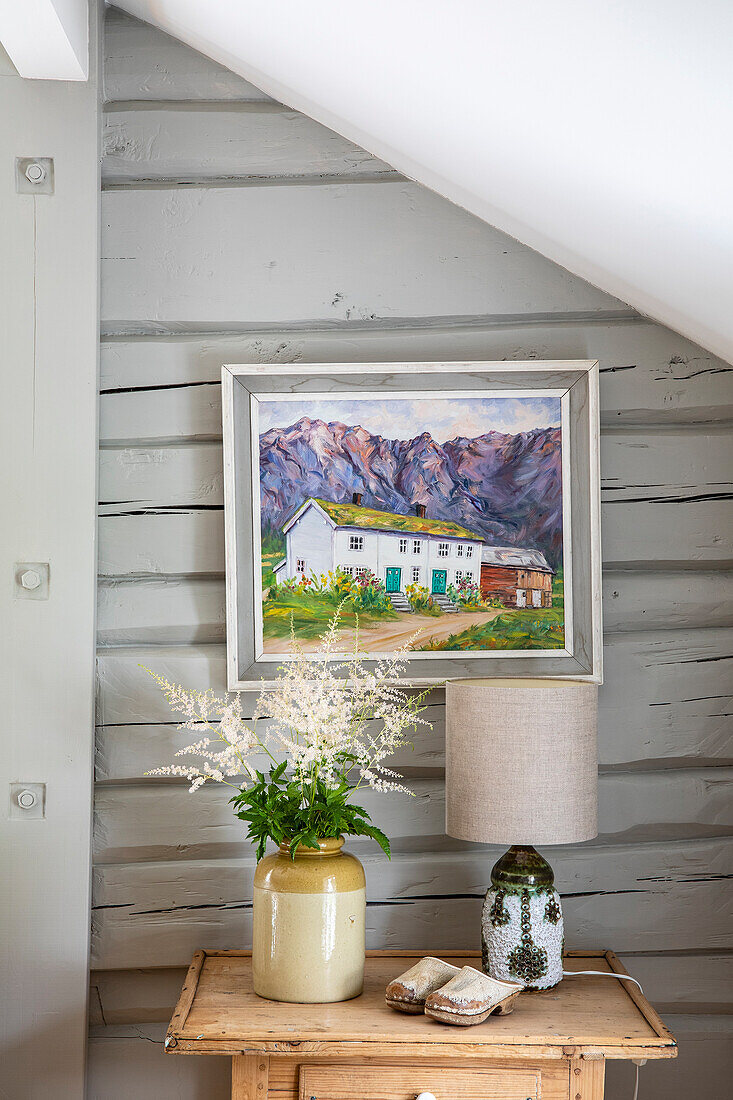 Painting on the wall, vase on chest of drawers, pitched roof with wood panelling