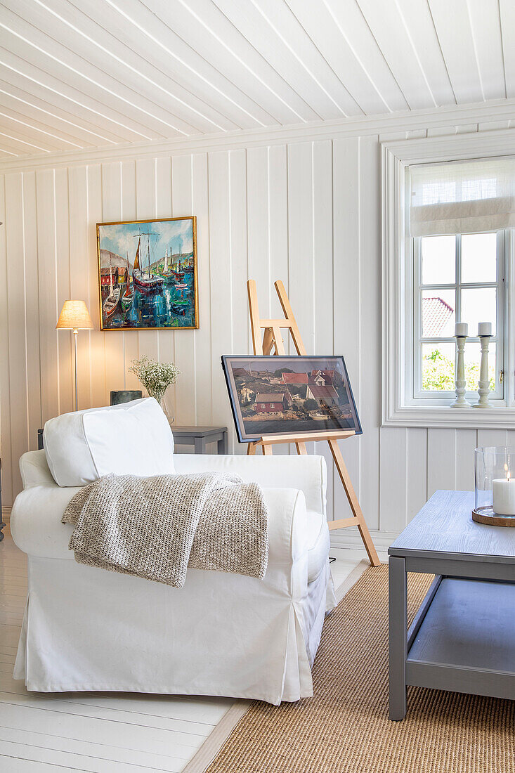 Bright country-style living room with easel and paintings