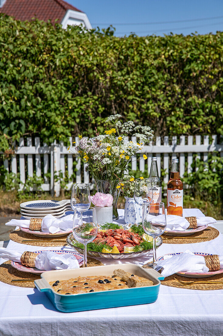 Gedeckter Gartentisch mit sommerlicher Dekoration und selbstgemachten Speisen