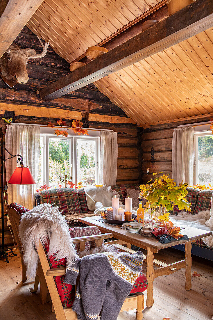 Herbstlich dekoriertes Wohnzimmer in einer Holzhütte
