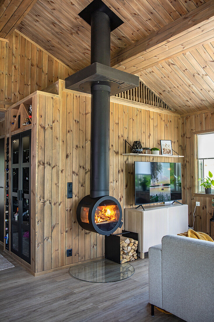 Wohnzimmer mit Holzverkleidung und hängendem Kamin