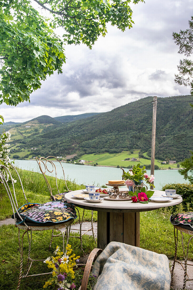 Idyllic garden breakfast at a wooden table with mountain view and lake panorama