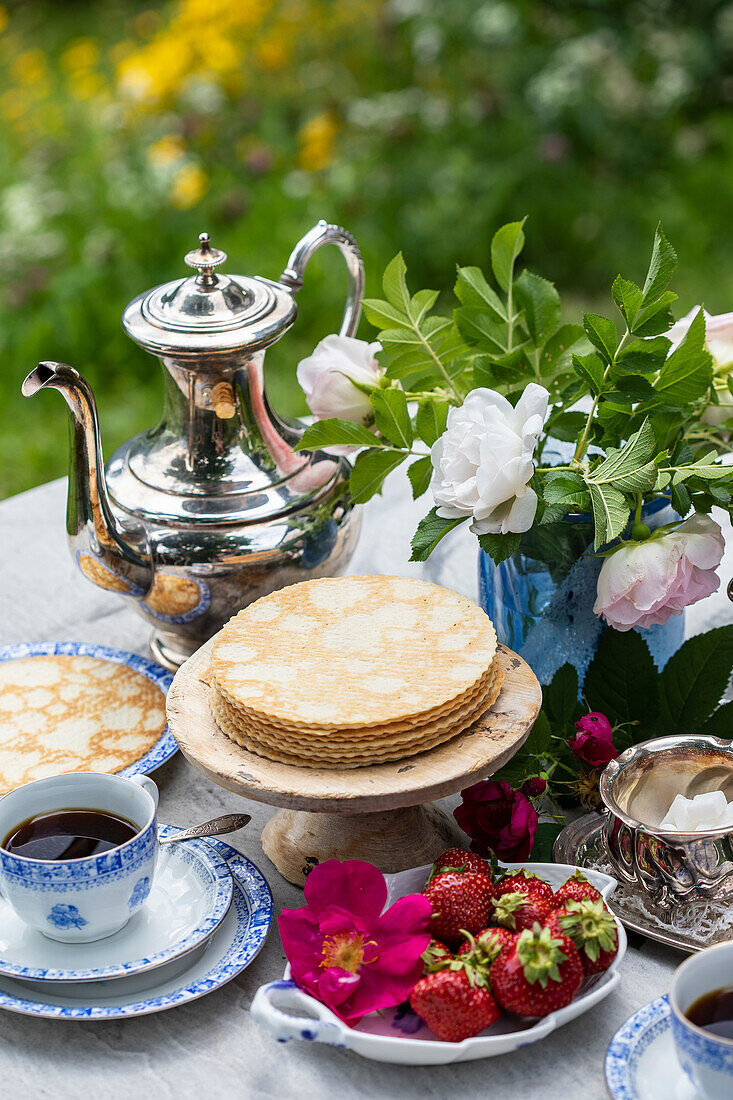 Breakfast in the garden with pancakes, strawberries and coffee
