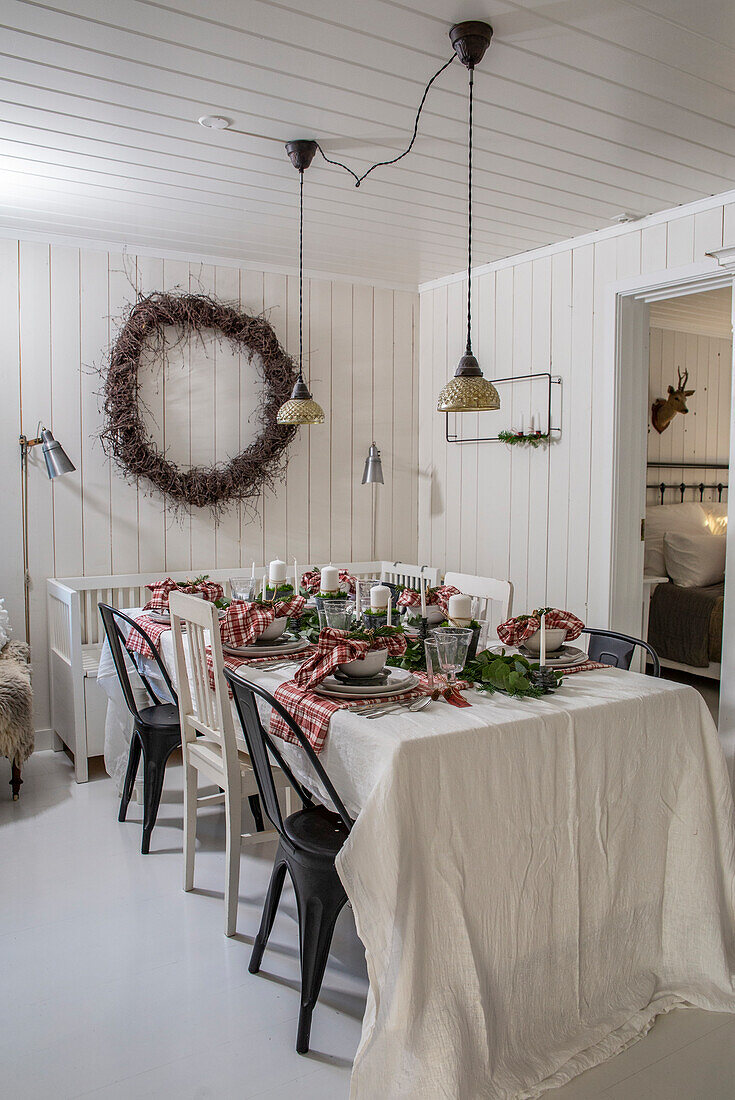 Christmas dining table with wreath and pendant lights in a white room