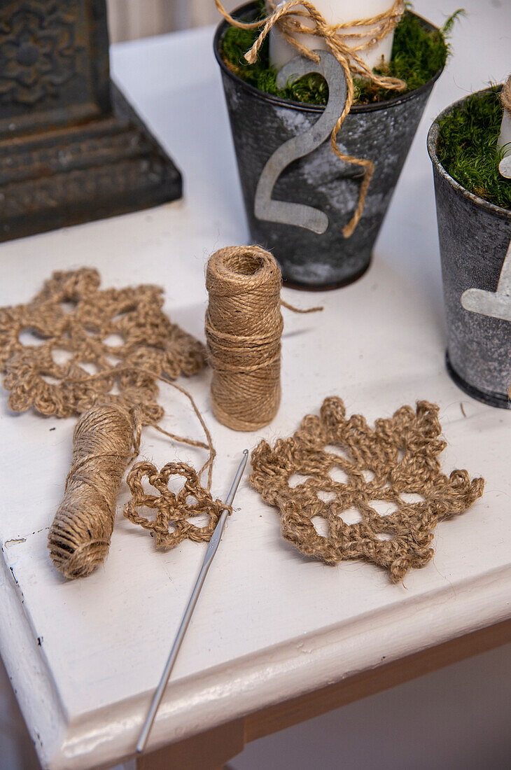 Crochet work with jute cord and finished coasters on a white table