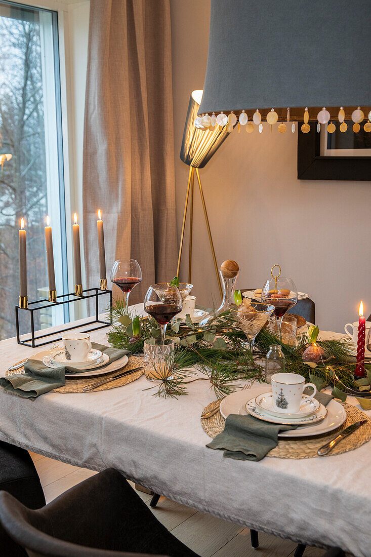 Festlich gedeckter Esstisch mit Kerzen und Tannenzweigen zur Weihnachtszeit