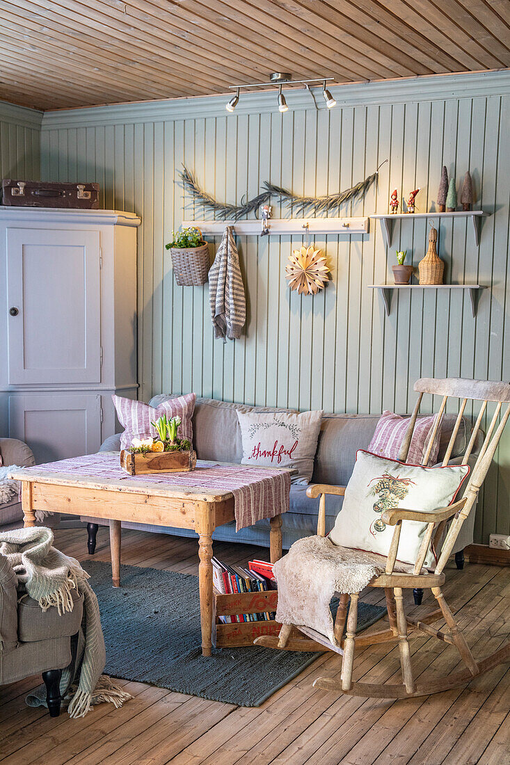 Rustic living room with wooden furniture and pastel green wall panelling