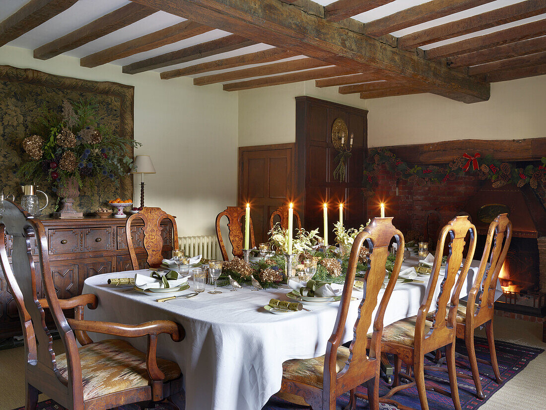 Festively laid Christmas table in a room with rustic wooden beams and antique furniture